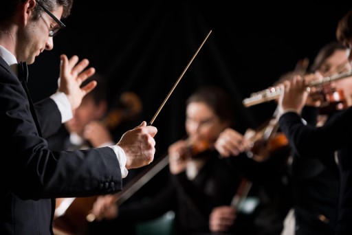 A conductor stands in front of an orchestra